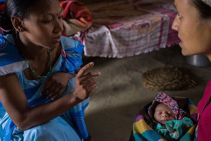 A health worker talks to a new mother holding her baby.