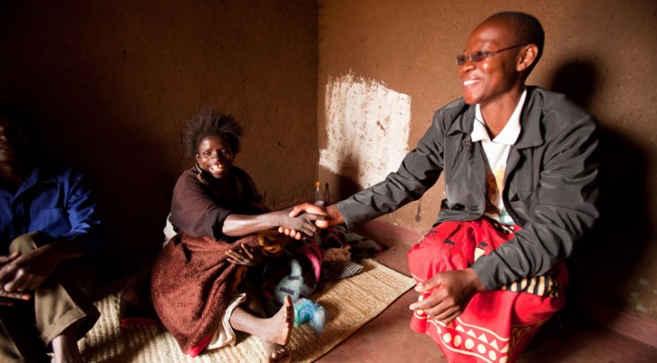 A health worker shakes hands with an AIDS patient in their home.