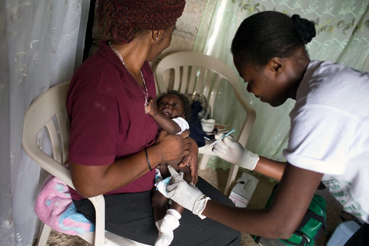 Ketcia Orilius, a community health worker in Robin, Haiti, gives 3-month-old Orelus Kerlens Melus a dose of vaccines