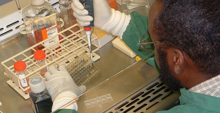 A lab technician works on a vaccine with test tubes.