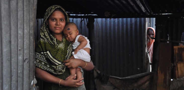 A mother holds her child in the doorway of their home.