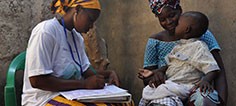 A health worker marks notes down from a mother and child examination