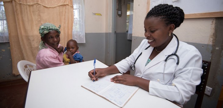 A doctor takes notes while a mother and her child sit nearby.