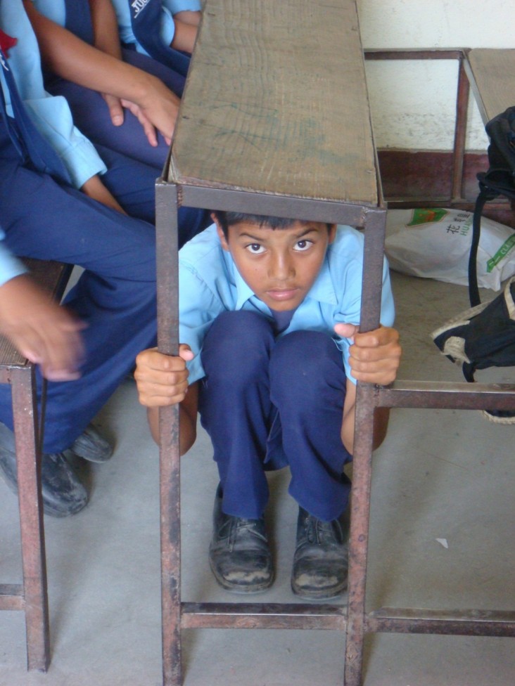 This student in Nepal demonstrates the appropriate reaction in the event of an earthquake.