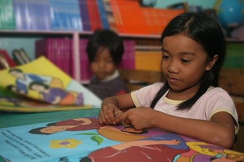 A young girl in the Philippines reads a book provided by a USAID-funded project. Photo Credit: USAID/Philippines