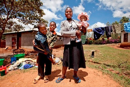 A happy family does laundry outside their home in Tanzania. Photo Credit: EGPAF/James Pursey