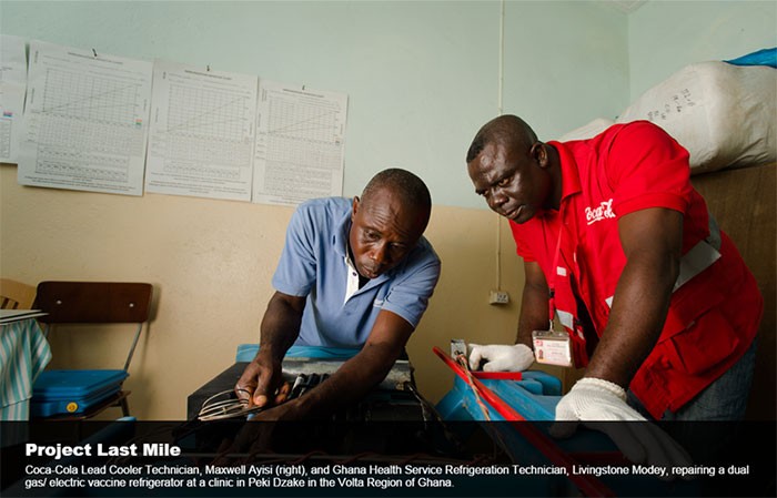 Coca-Cola Lead Cooler Technician, Maxwell Ayisi, and Ghana Health Service Refrigerator Technician repair a vaccine refrigerator.