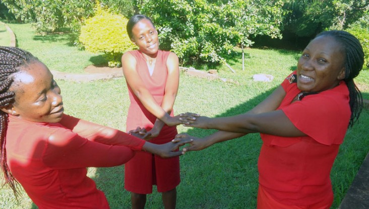 Three women dressed in red hold hands in a circle