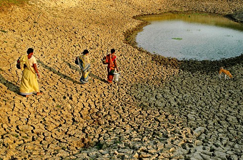Three women finally reach their water source, a low water level lake in India.