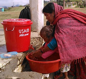 A mother in Nepal washes her child's hands