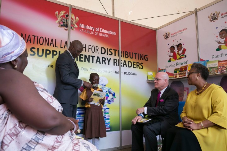 Amb. Robert Jackson listens to a child read one of the books distributed