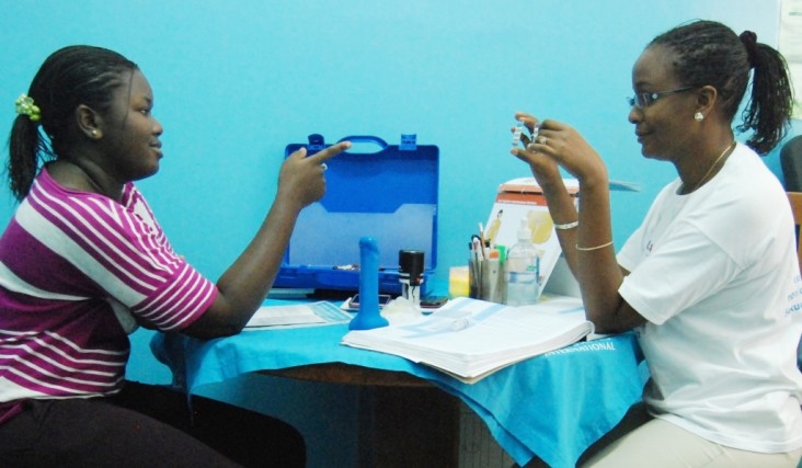 Une conseillère en planification familiale montre des contraceptifs oraux à une étudiante