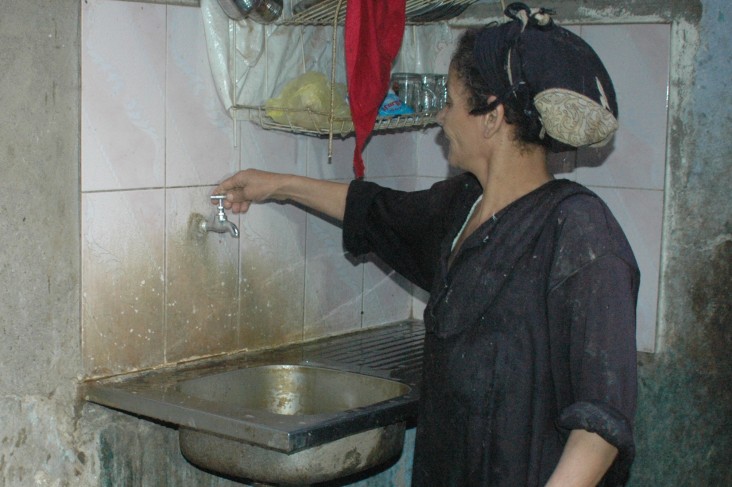 Woman turns on water faucet in her home