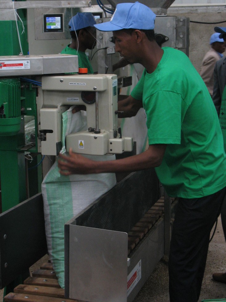 A worker at the new fertilizer blending facility operates the machine to seal the bags of finished product after the raw compone