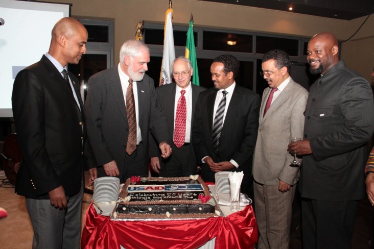 Thomas Staal, Donald Booth, and Ethiopian officials stand around USAID cake