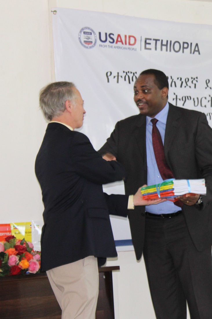 USAID Ethiopia Mission Director Dennis Weller (left) presents some of the new mother tongue reading materials to Minister of Edu