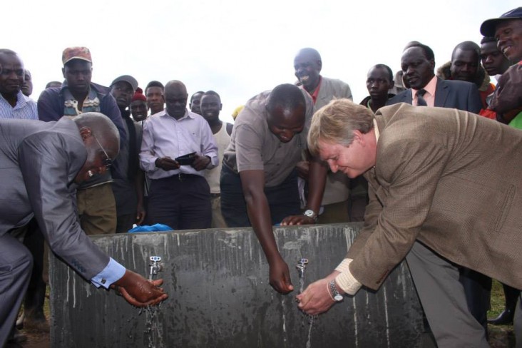 USAID and Government of Kenya representatives wash their hands using an outdoor faucet
