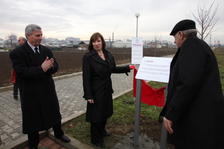Ambassador Jacobson unveils a plaque commemorating DEMI’s park and sidewalk project