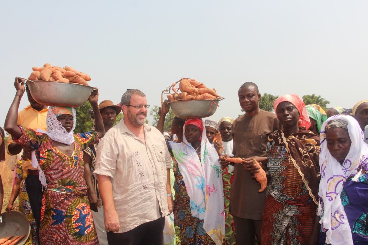 Andy Karas, Mission Director, with women carrying Orange flesh sweet potato 
