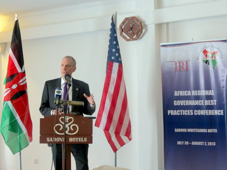 US Ambassador to Kenya speaks behind a podium flanked by Kenyan and American flags