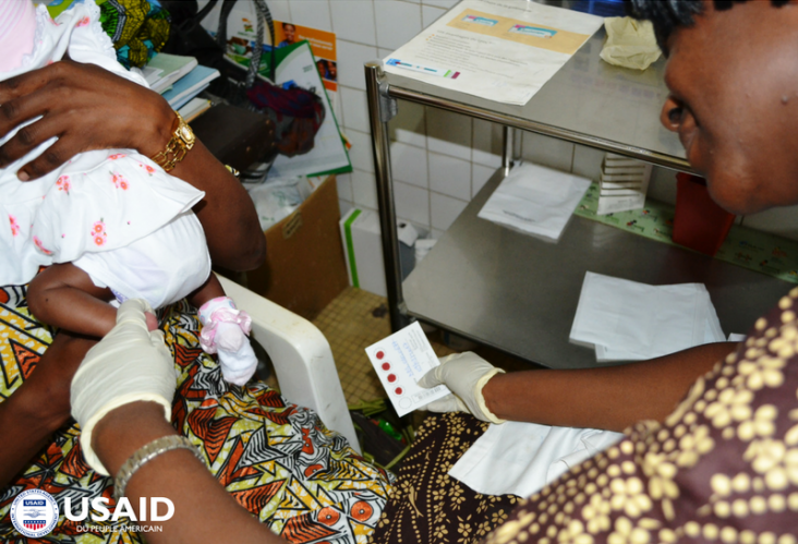A health worker collects dried blood samples from an infant 