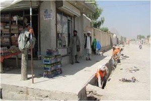 Haji Gul Agha watches laborers outside his shop in Mirwais Mina, while they shovel the final remnants of sewage and trash from t