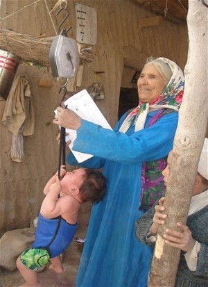 A community health worker checks a child’s weight gain during a growth monitoring session in Jawzjan Province.