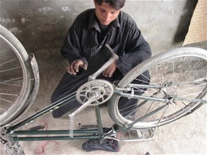 Ashraf Khan fixes a bicycle in his shop, which he opened after completing a USAID-funded bicycle repair course. The shop provide