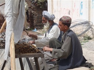 A young man learning the skills of the steel cutting trade from a master. Both men are employed on a USAID-funded project.