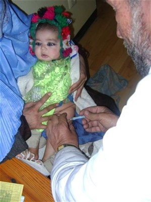 An Afghan doctor administers a vaccination to a baby girl in Farza District to protect her from communicable diseases.