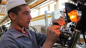 A young apprentice installing electronics at the USAID-funded motorbike assembly project.