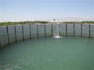 Water from Al Buroni University's new solar water pump spills into a concrete reservoir that feeds the lower farm.