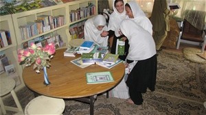 Girls at Fatima Balkhi Girls' High School in Mazar-e-Sharif happily unpacking books recieved through USAID funds.