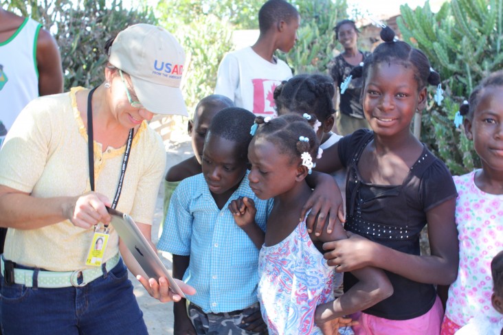 USAID/Haiti GIS Specialist Anna Brenes shows local children photos of the nearby road she mapped.