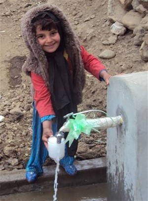 A new piped water system fulfills a basic need for residents. Here a young girl collects a glass of drinking water from newly co