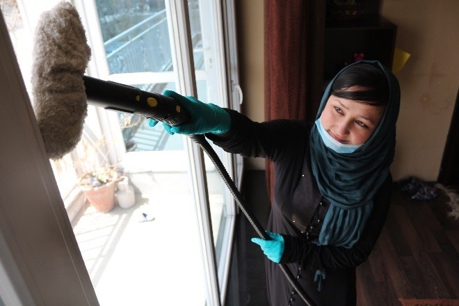 Aqela Faiz Ahmad, a housecleaner employed by Shahre Safa, dusts a window at a client’s house.