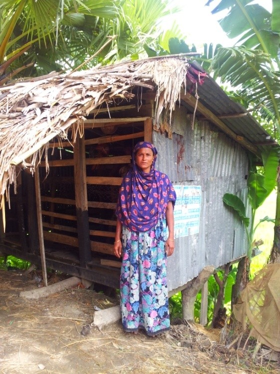 Photo of beneficiary and her chicken coop started with funds saved