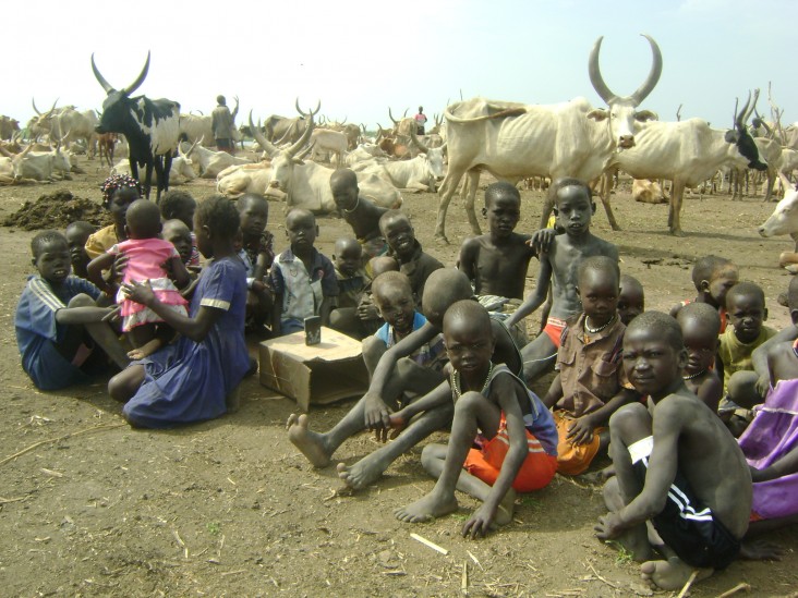 Children in a cattle camp in South Sudan learn their mother tongue with a digital audio player