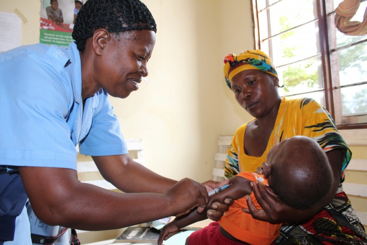 A nurse gives a child an immunization shot while his mother holds him.