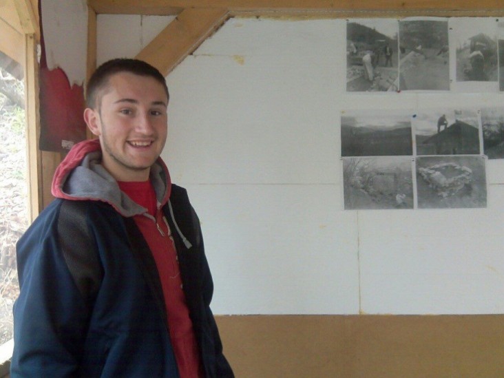 Sulejman Abazović, youth leader and peace activist in Bistrica, stands next to images of local youth working together to improve their communities. 