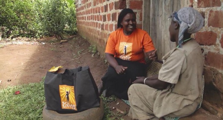 A Solar Sister entrepreneur, left, describes how she uses her “business in a bag” to a customer.