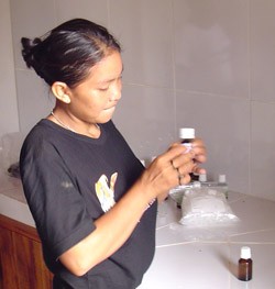 A young woman of the Uru-eu-wau-wau tribe bottles and labels copaiba oil.