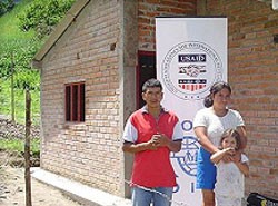 Flor and José Baca pose in front of their new home in Los Andes de Sotomayor, Nariño, which USAID helped them build with their o