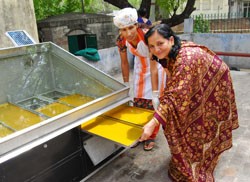 Indian women trained through a USAID program prepare mango bars using a solar dryer unit