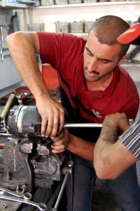 Baghdad Mechanic Ahmed Hamoody repairs an auto air conditioning motor with assistance from an employee