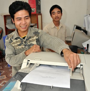 Dang Van Toan, left, operates the new photocopy machine in his computer services and copy shop in Me.