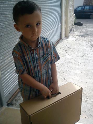 A young Syrian boy receives a box of clothing at a USAID-supported distribution site.