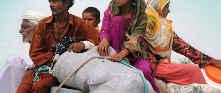 Pakistanis return home with their belongings to Bassera village in Punjab province in August 2010 as flood waters recede.