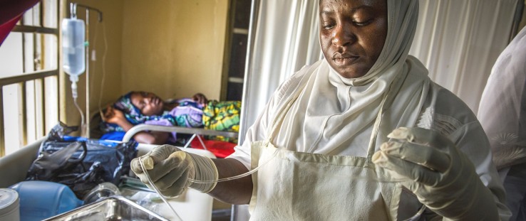 A nurse at a Nigerian health care facility gets ready to cut a mother’s umbilical cord.