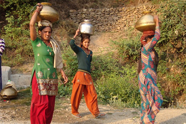 Three women carry jugs of water on their heads
